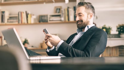 glad mand sidder med sin telefon på kontor